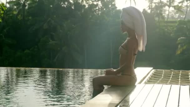 プールの椅子でゆったりと寛げるタオルローブを着た美しい女性 — ストック動画
