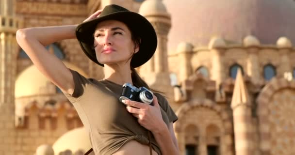 Турист стоит с фотоаппаратом возле отеля — стоковое видео