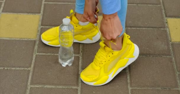 Close-up of woman tying shoelaces on white sneakers. Girl squatting on sidewalk. — Stock Video