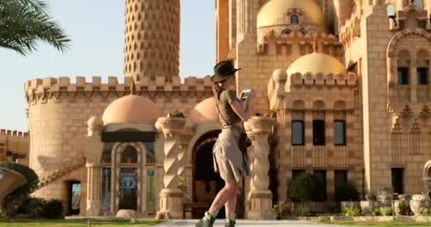 Красива жінка дивиться на камеру і фотографується на фоні мечеті — стокове відео