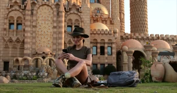 Bella ragazza in stile cowboy si siede sull'erba, con il phone.mosque — Video Stock