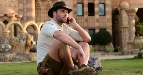 Τουρίστας μιλάει στο τηλέφωνο, ενώ κάθεται στο τζαμί γρασίδι, Ινδία — Αρχείο Βίντεο