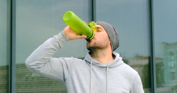 L'athlète boit de l'eau au stade après l'entraînement. entraîneur de sport dans un chapeau — Video