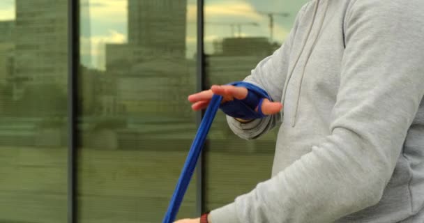 Svalnatý bojovník kickbox s modrými obvazy na pozadí okna — Stock video