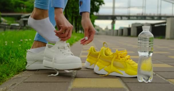 Nahaufnahme von Läuferschuhen. Mädchen zieht Sportschuhe auf der Straße an, Flasche — Stockvideo
