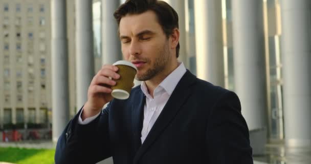 Empresário num prédio de escritórios. está bebendo café e olha para o relógio — Vídeo de Stock