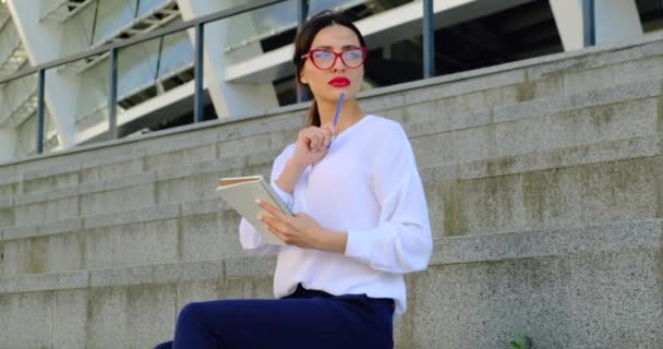 Förförisk flicka med rött läppstift och glasögon vilar på gatan, Freelancer — Stockvideo