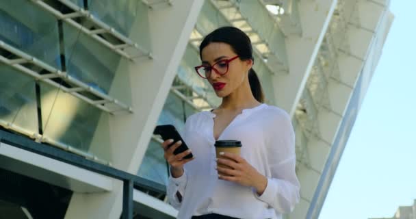 Portret van sexy en zelfverzekerde zaken in glazen vrouw met koffie, telefoon — Stockvideo