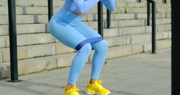 Squat. sportivo donna in moda vestiti squatting con band ragazza ginnasta formazione — Video Stock