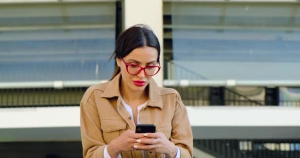 Mooi meisje met een telefoon wacht op haar vriendje op een date. Rode lippen — Stockvideo