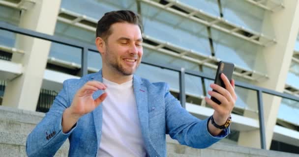 Schöner junger Mann mit Smartphone im Gespräch via Videolink mit einem Mädchen — Stockvideo