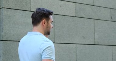 Genç işadamı akıllı telefonunu kaydırırken yürüyor