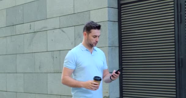 Jonge zakenman loopt tijdens het scrollen van zijn smartphone — Stockvideo