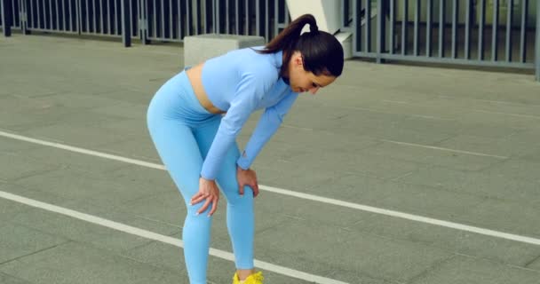 Müde Frau sitzt und ruht nach dem Training. Läuferin macht Pause. — Stockvideo