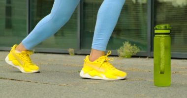 Spor kıyafetli güzel bir kız atlıyor ve su içen bir kadın esniyor.