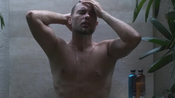 Красивый мужчина с голым туловищем принимает душ в тропическом доме — стоковое видео