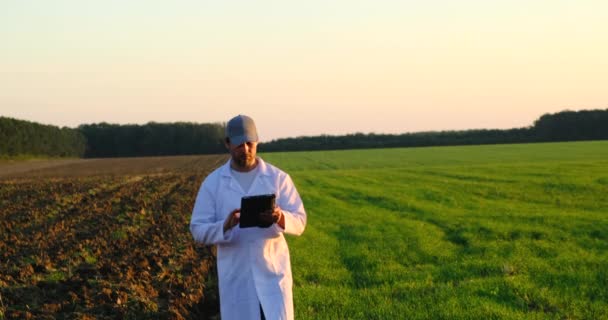 Un agrónomo examina el suelo hace una nota en la tableta Agricultura, ecología — Vídeo de stock