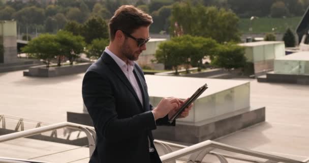 Knappe zakenman in pak met mobiele telefoon op straat in de buurt van kantoor — Stockvideo