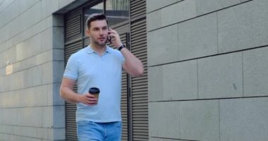 Kahveli gülümseyen adam ofisin yakınında cep telefonuyla konuşuyor. Güzel gün