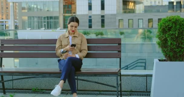 Mujer disfrutando en el día de otoño mientras bebe café. Chica sentada en banco de madera — Vídeos de Stock