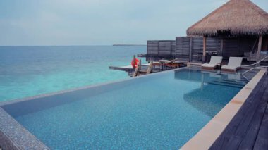 Maldivler 'deki turkuaz denize bakan sonsuz havuzlu lüks bir tatil köyü. Manzara, tropikal cennet, tatil, ada dinlenme, dünya çapında Bora Bora, Seyşeller ve Fiji gibi tatil beldelerini temsil eder.