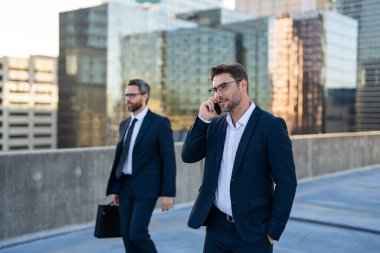 Başarılı girişimci şehir manzaralı çatıda yürürken telefonla konuşuyor. Çantası olan başka bir işadamı da onu takip ediyor. Sahne, liderlik, finans, hırs ve başlangıç başarısını simgeler