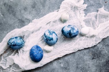 Mavi, koyu mavi paskalya yumurtaları gri masada.