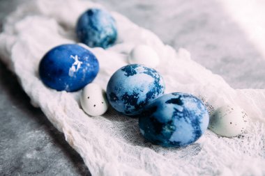 Mavi, koyu mavi paskalya yumurtaları gri masada.