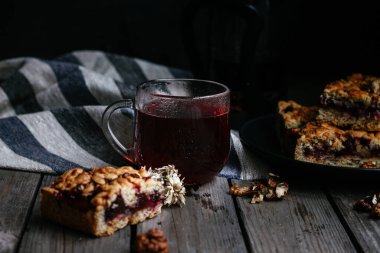 Siyah üzümlü kısa hamurlu pasta ve koyu arkaplanda çay.