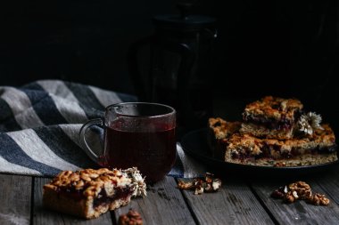 Siyah üzümlü kısa hamurlu pasta ve koyu arkaplanda çay.