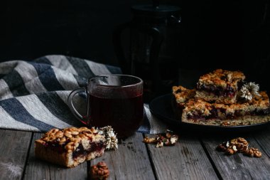 Siyah üzümlü kısa hamurlu pasta ve koyu arkaplanda çay.