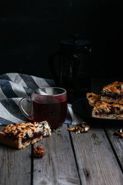 Siyah üzümlü kısa hamurlu pasta ve koyu arkaplanda çay.