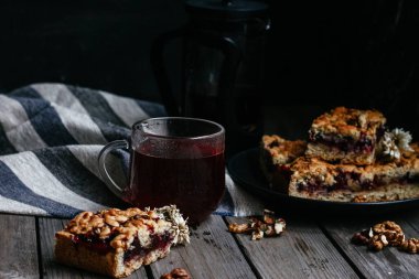 Siyah üzümlü kısa hamurlu pasta ve koyu arkaplanda çay.