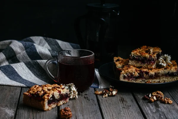 Siyah üzümlü kısa hamurlu pasta ve koyu arkaplanda çay.