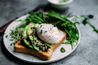 Poached egg with avocado salad, microgreen and arugula