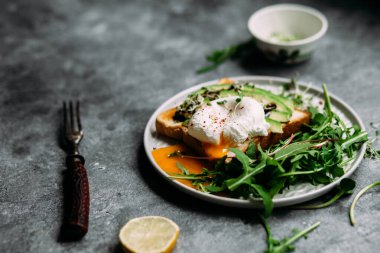 Poached egg with avocado salad, microgreen and arugula
