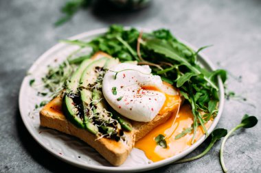 Poached egg with avocado salad, microgreen and arugula