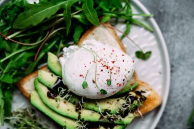 Poached egg with avocado salad, microgreen and arugula