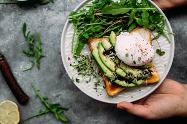Poached egg with avocado salad, microgreen and arugula