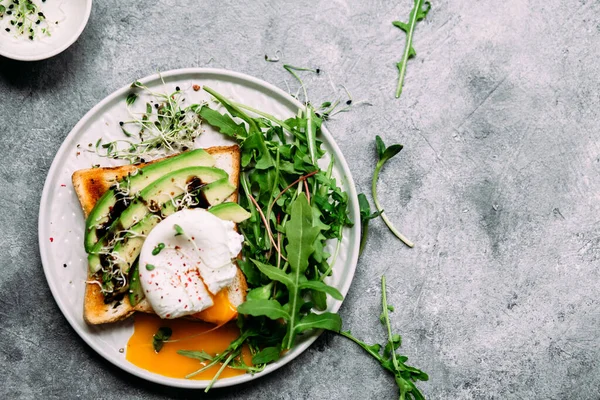 Poached egg with avocado salad, microgreen and arugula