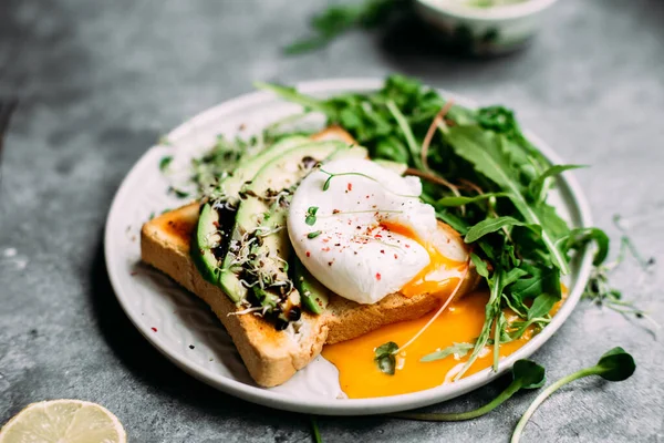 Poached egg with avocado salad, microgreen and arugula