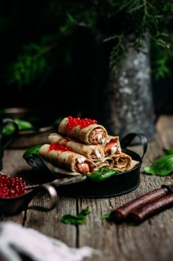  Tahta arka planda kırmızı havyar balığı ve krem peynirli krep.