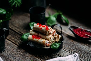  Tahta arka planda kırmızı havyar balığı ve krem peynirli krep.