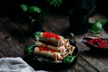  Tahta arka planda kırmızı havyar balığı ve krem peynirli krep.