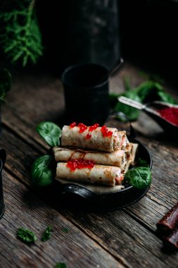  Tahta arka planda kırmızı havyar balığı ve krem peynirli krep.