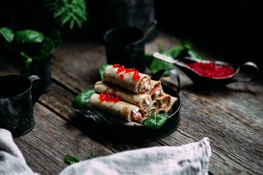  Tahta arka planda kırmızı havyar balığı ve krem peynirli krep.