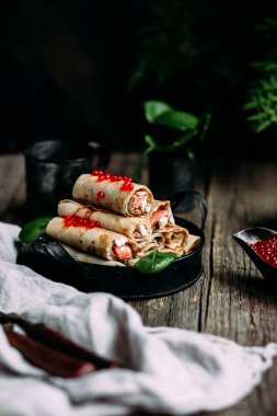  Tahta arka planda kırmızı havyar balığı ve krem peynirli krep.