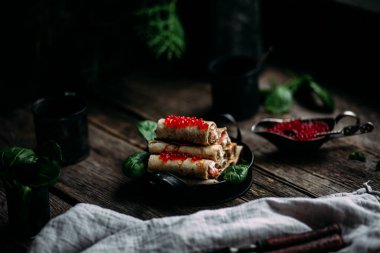  Tahta arka planda kırmızı havyar balığı ve krem peynirli krep.