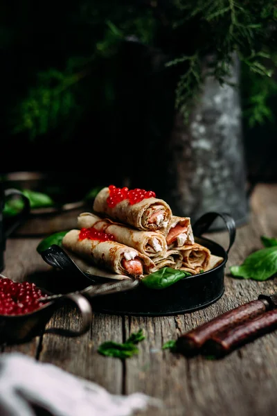  Tahta arka planda kırmızı havyar balığı ve krem peynirli krep.