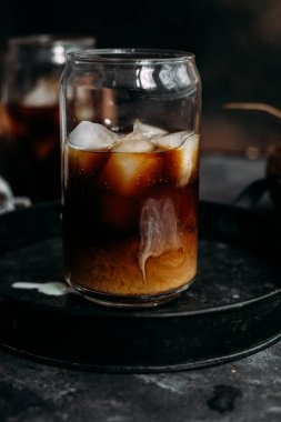 Şeffaf bardakta buzlu kahve ve hindistan cevizi sütü.